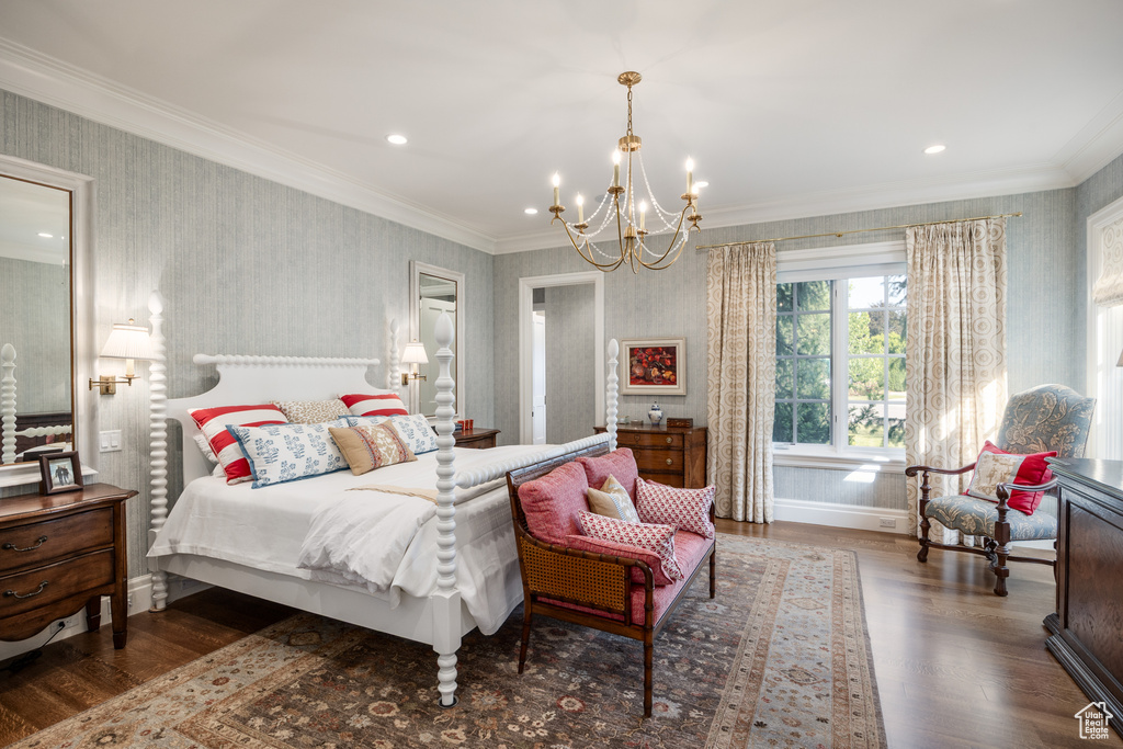 Bedroom with wallpapered walls, a chandelier, wood finished floors, baseboards, and ornamental molding