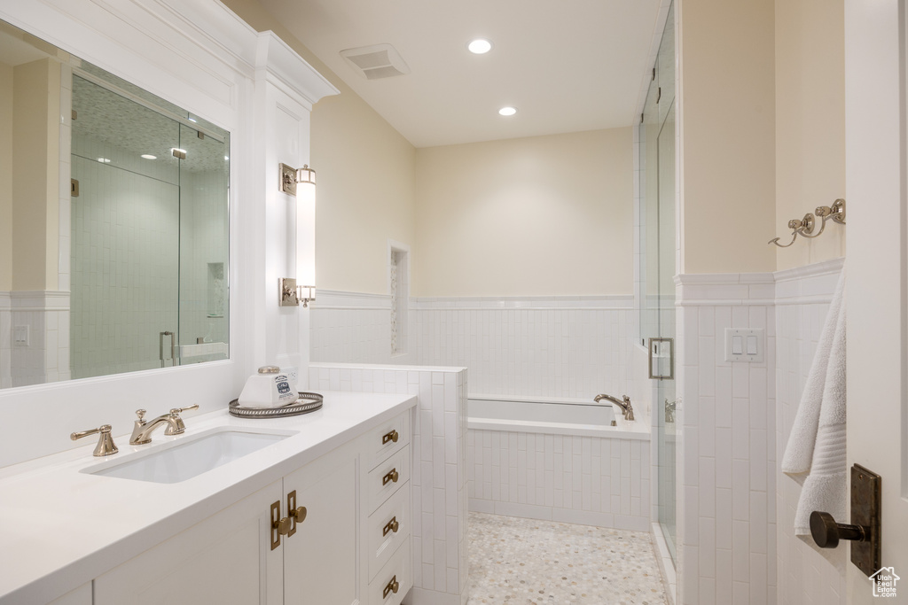 Bathroom with vanity, a bath, a stall shower, recessed lighting, and a wainscoted wall