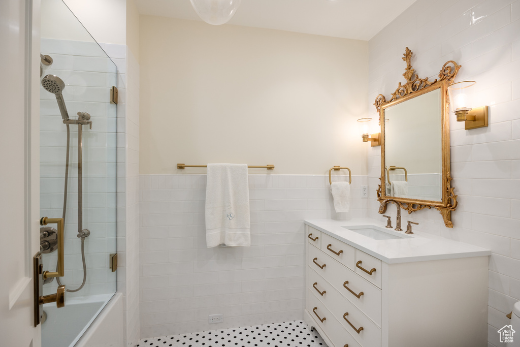 Bathroom with vanity, tub / shower combination, and tile walls