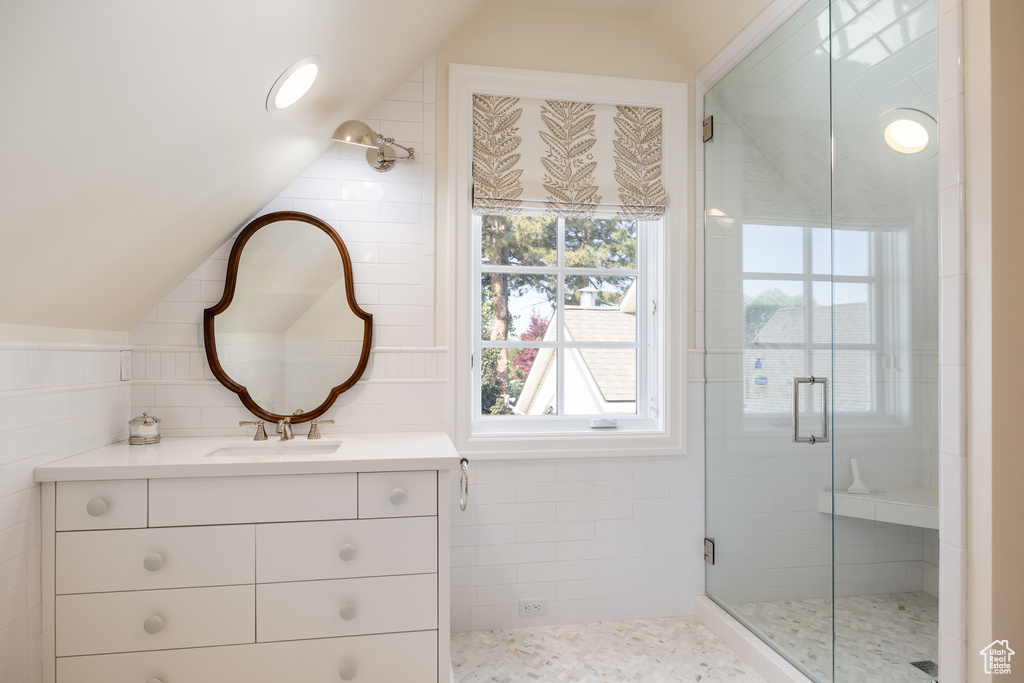 Bathroom featuring lofted ceiling, a shower stall, vanity, and tile walls