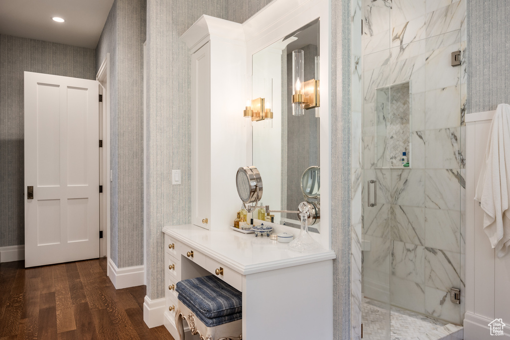 Full bathroom with wood finished floors, a marble finish shower, wallpapered walls, baseboards, and vanity
