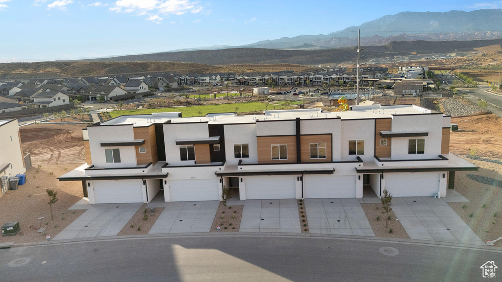 Townhome / multi-family property featuring stucco siding, a mountain view, a garage, driveway, and a residential view