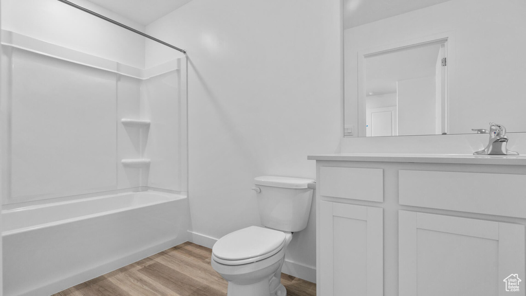 Bathroom with wood finished floors, vanity, toilet,  shower combination, and baseboards