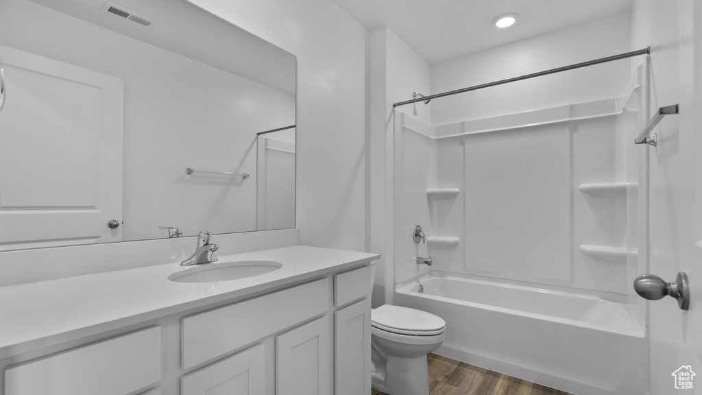 Bathroom featuring wood finished floors, vanity, shower / bath combination, and toilet