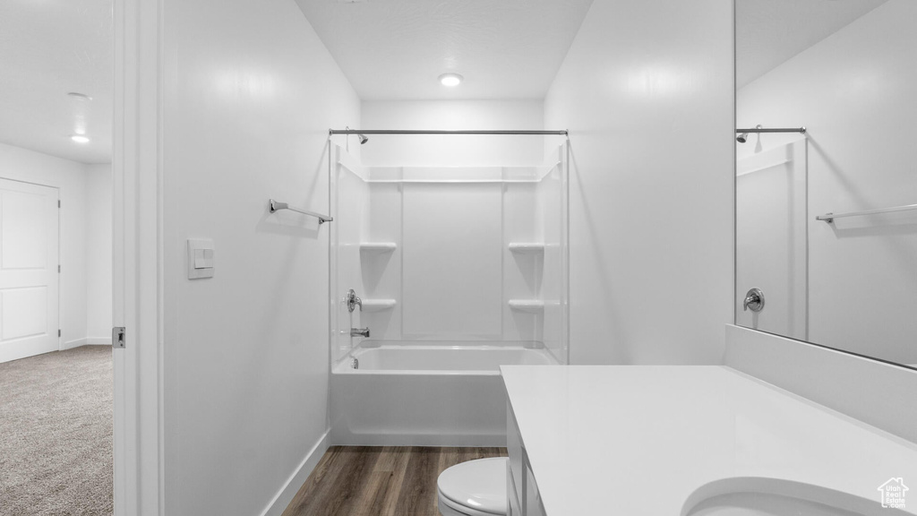 Bathroom featuring bathing tub / shower combination, toilet, vanity, baseboards, and wood finished floors