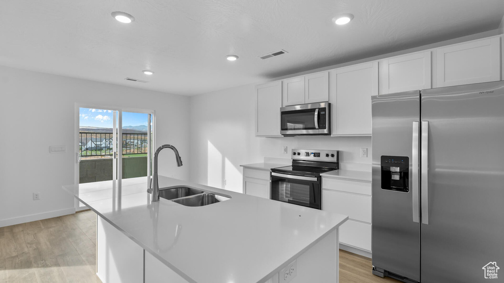 Kitchen featuring appliances with stainless steel finishes, a sink, light wood-style flooring, white cabinets, and recessed lighting