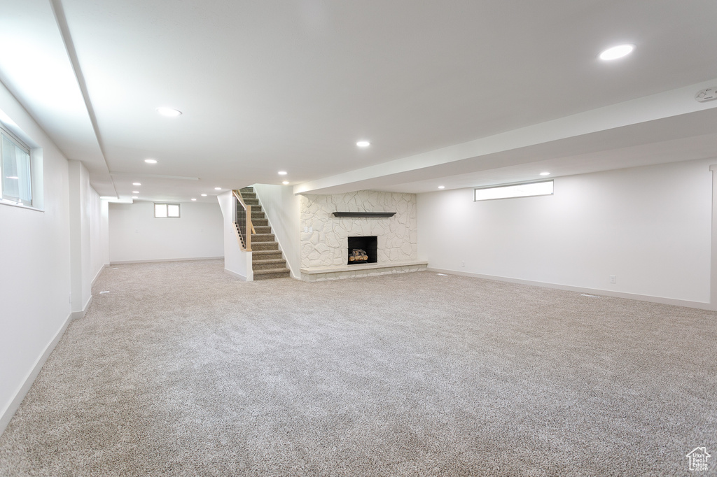 Below grade area featuring recessed lighting, carpet flooring, stairway, baseboards, and a fireplace