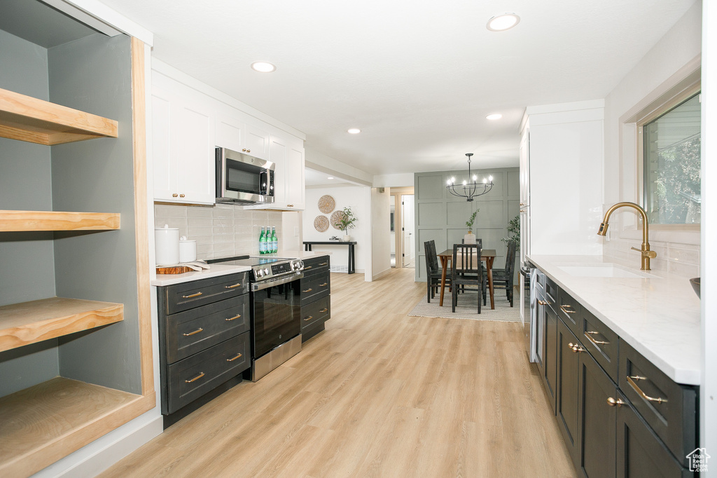 Kitchen featuring appliances with stainless steel finishes, a sink, open shelves, white cabinetry, and light wood-type flooring
