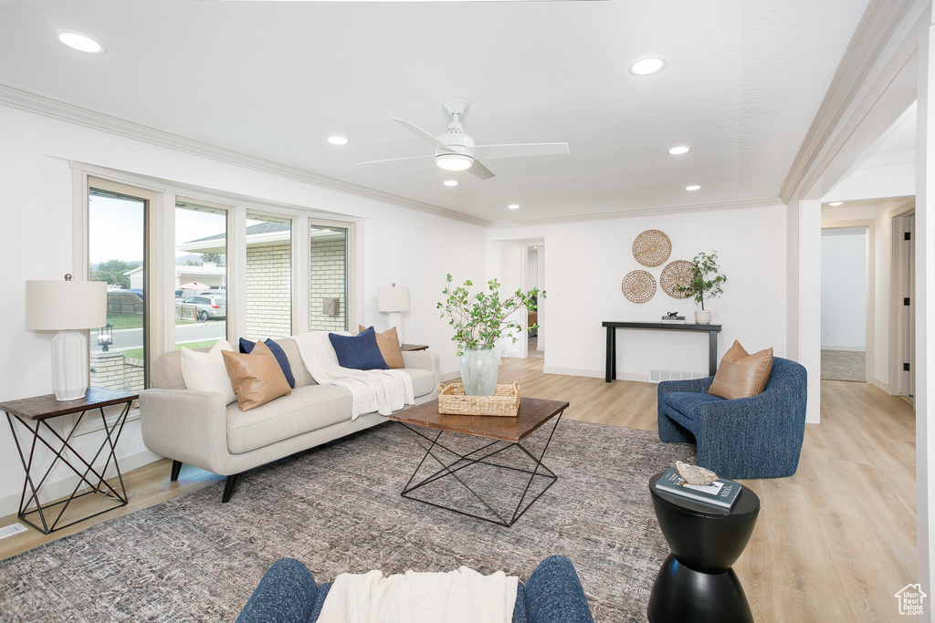 Living area featuring light wood-style floors, ceiling fan, recessed lighting, ornamental molding, and baseboards