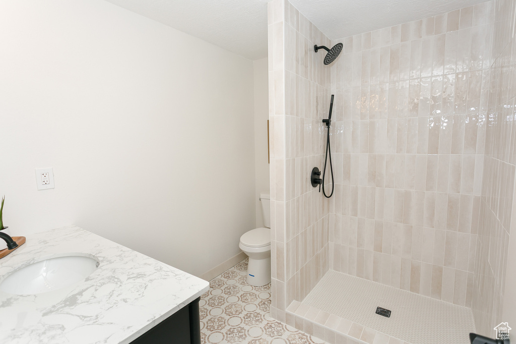Bathroom with vanity, a tile shower, and toilet