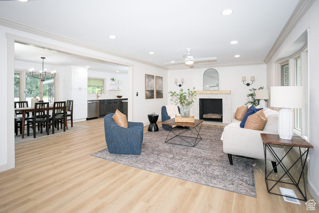Living room with a chandelier, light wood-style flooring, recessed lighting, a fireplace with flush hearth, and ornamental molding