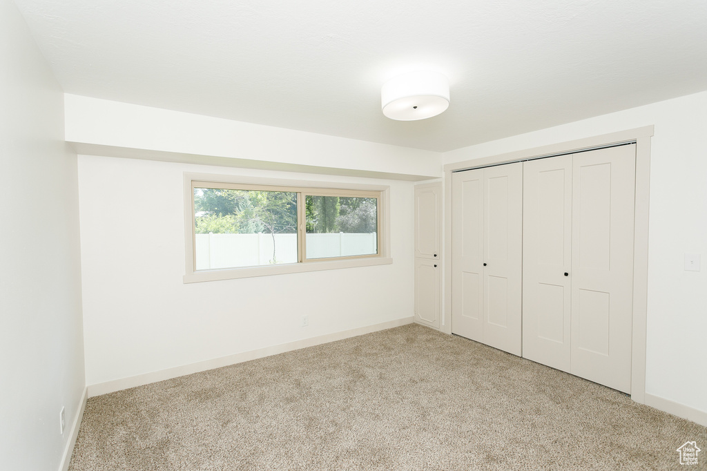Unfurnished bedroom with carpet, a closet, and baseboards