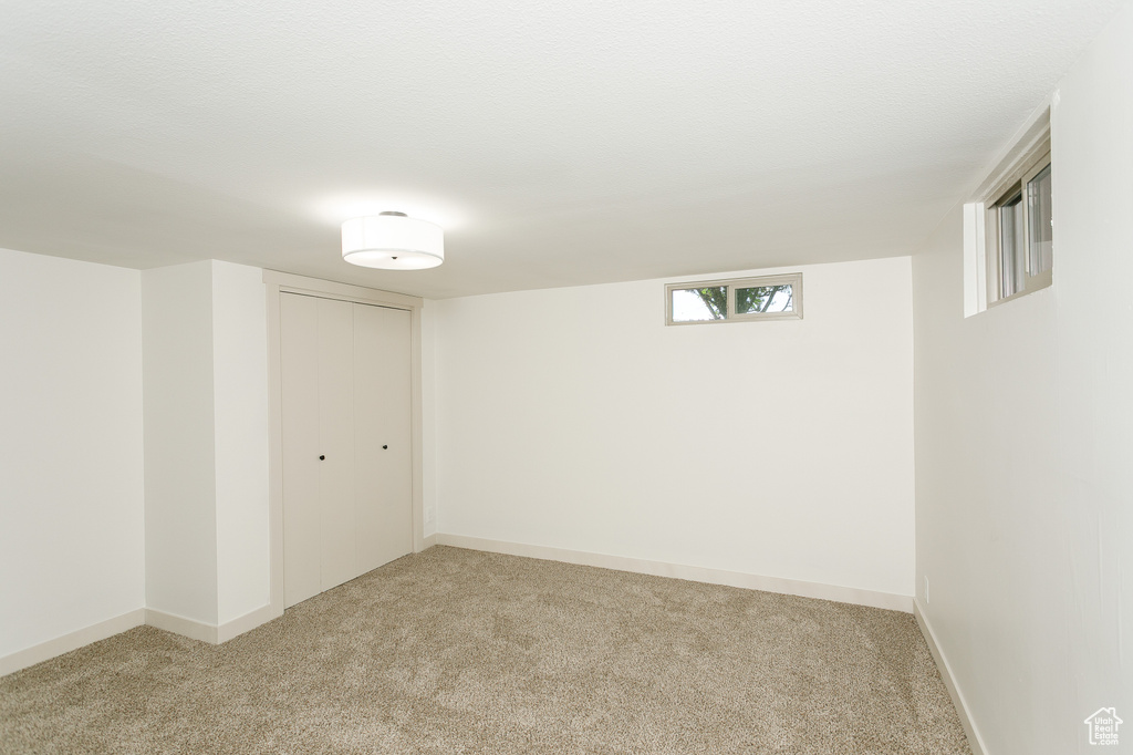 Basement featuring light colored carpet and baseboards