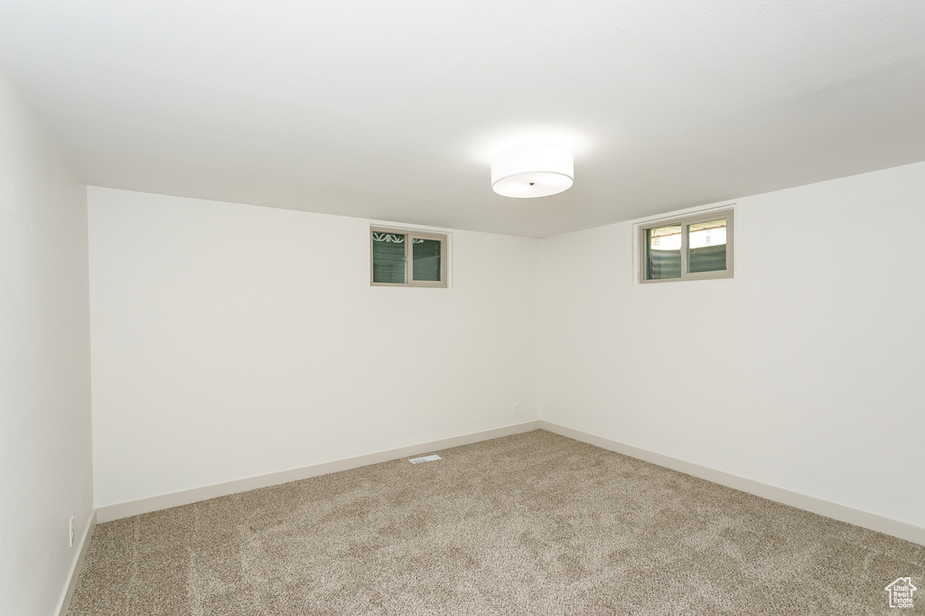 Below grade area featuring light carpet and baseboards