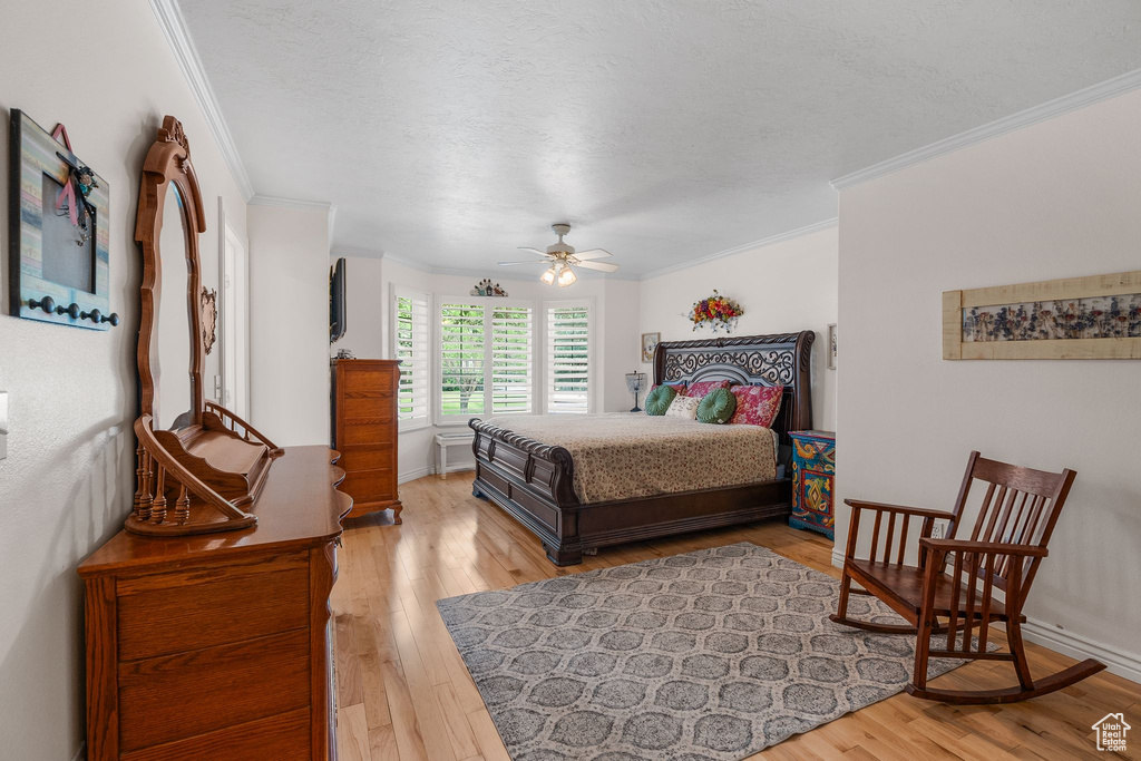 Bedroom featuring ornamental molding, light wood-style floors, a textured ceiling, and baseboards