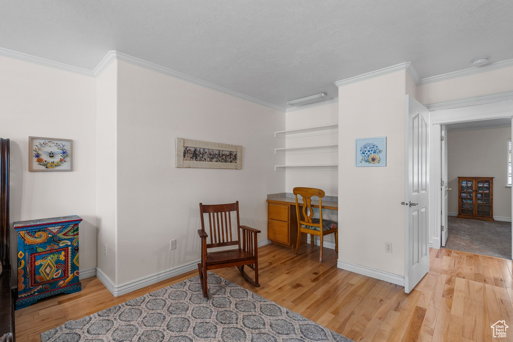 Living area with ornamental molding, wood finished floors, and baseboards