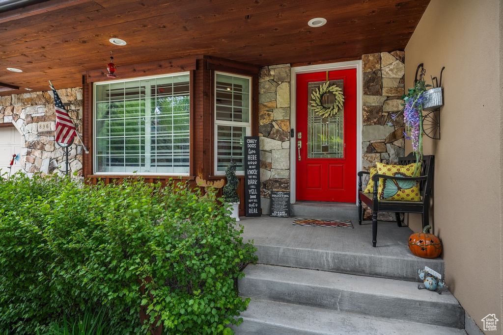 Property entrance featuring stone siding, a porch, and stucco siding