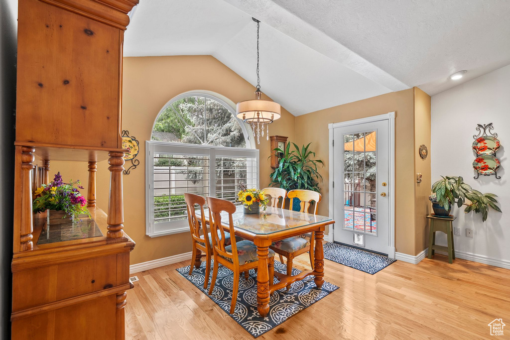 Dining area featuring vaulted ceiling, light wood finished floors, baseboards, and a chandelier