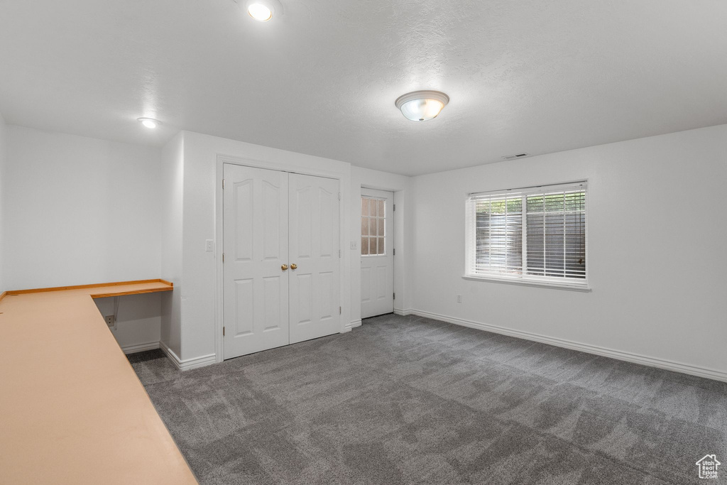 Unfurnished bedroom featuring carpet flooring, a closet, baseboards, and a desk