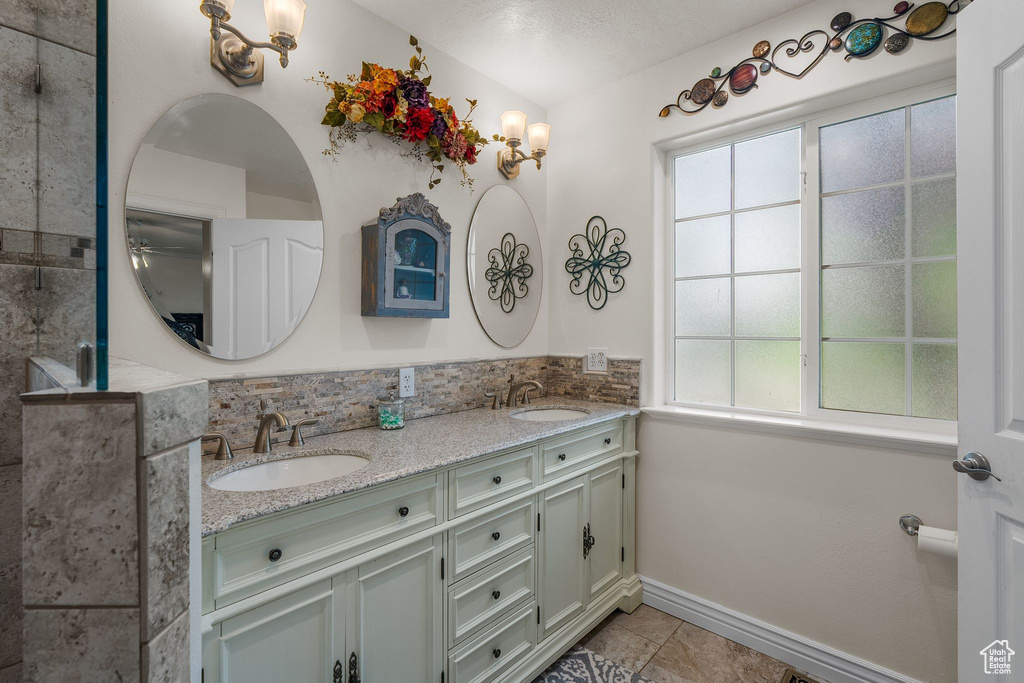 Bathroom featuring double vanity, plenty of natural light, tile patterned flooring, and baseboards