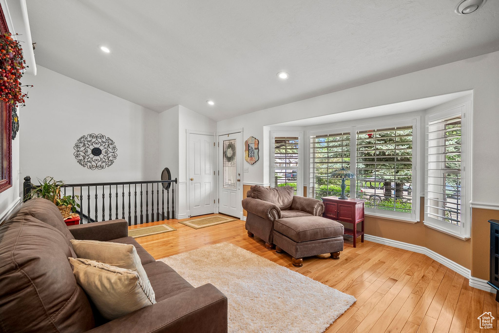 Living area with lofted ceiling, light wood finished floors, baseboards, and recessed lighting