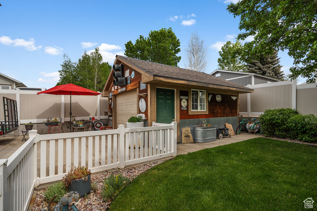 View of front of home featuring an outdoor structure, a garage, and roof with shingles