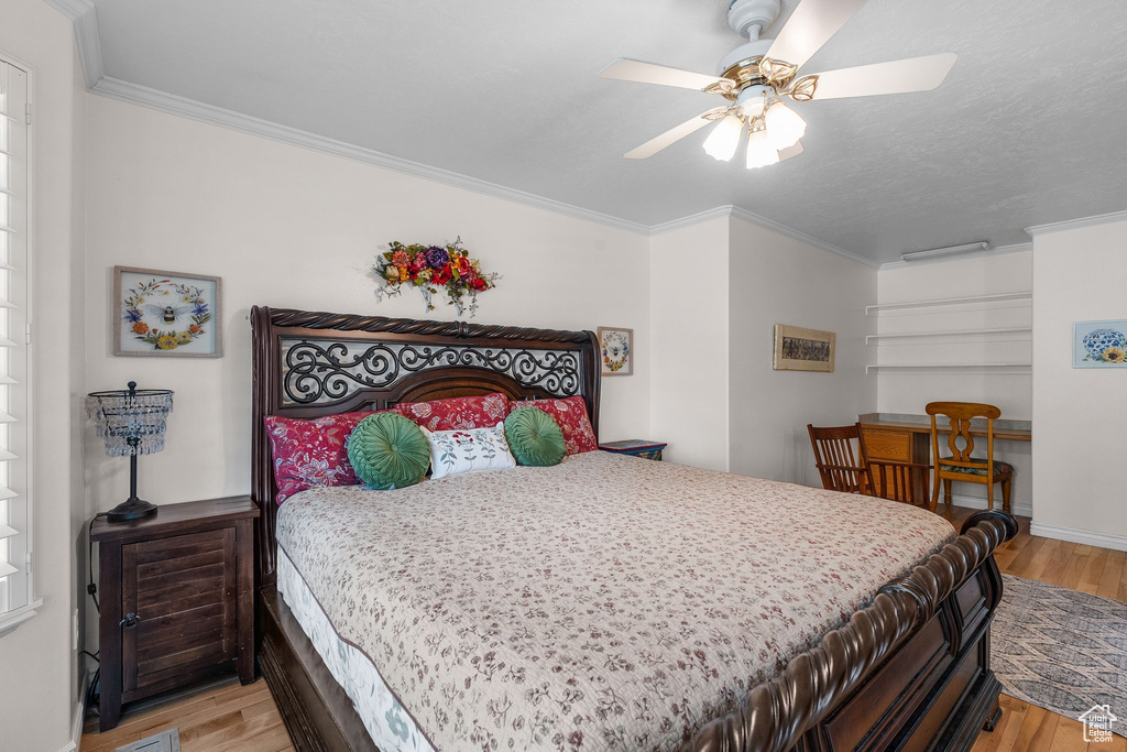 Bedroom featuring light wood finished floors, ornamental molding, a ceiling fan, and baseboards
