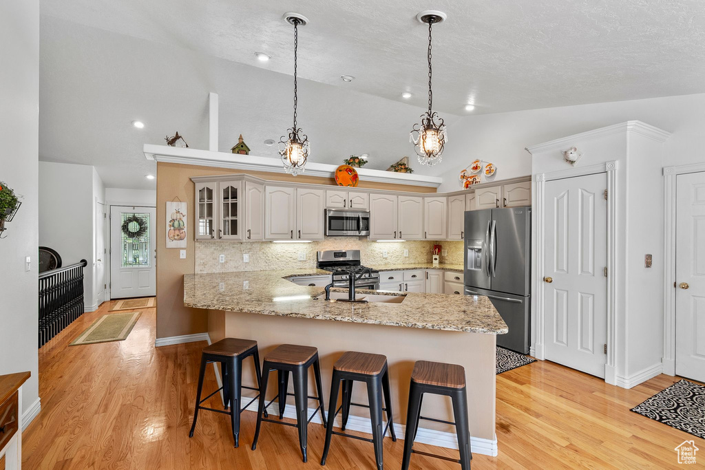 Kitchen featuring stainless steel appliances, a peninsula, a sink, a kitchen breakfast bar, and glass insert cabinets