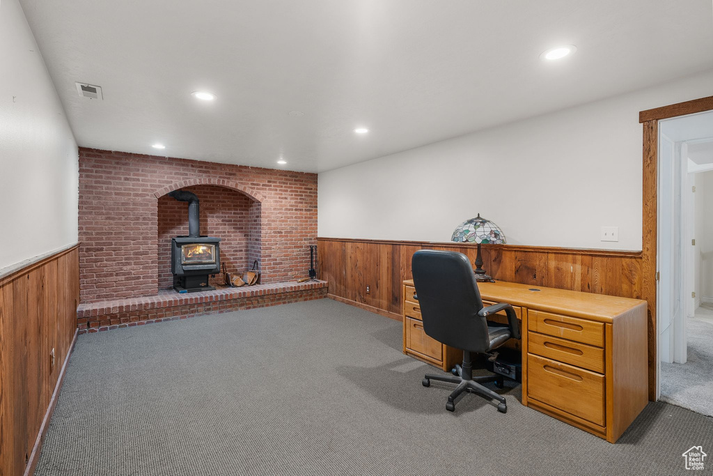 Carpeted office space with a wainscoted wall, wooden walls, a wood stove, and recessed lighting