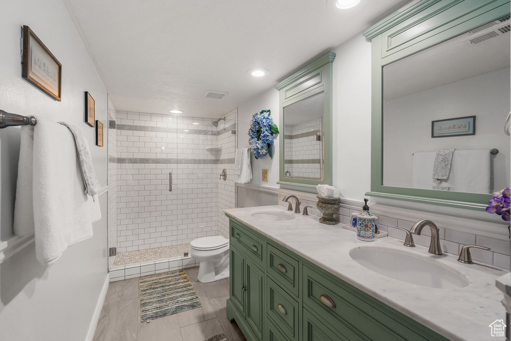 Full bath featuring a stall shower, double vanity, toilet, and recessed lighting
