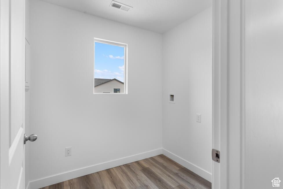 Laundry area with wood finished floors, baseboards, and hookup for a washing machine