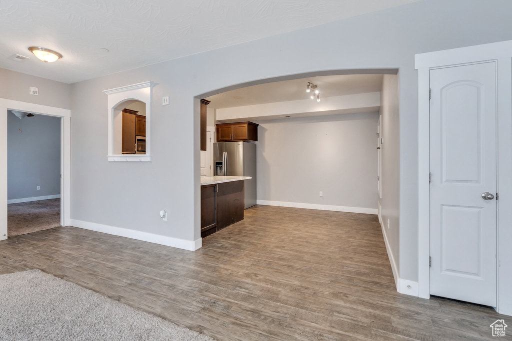 Unfurnished living room with baseboards, wood finished floors, and arched walkways