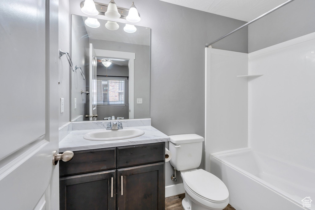 Bathroom with toilet, vanity,  shower combination, and a ceiling fan