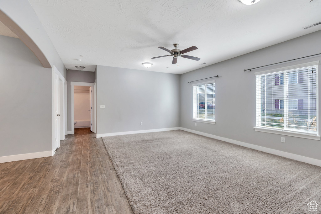 Empty room featuring baseboards, ceiling fan, wood finished floors, and arched walkways