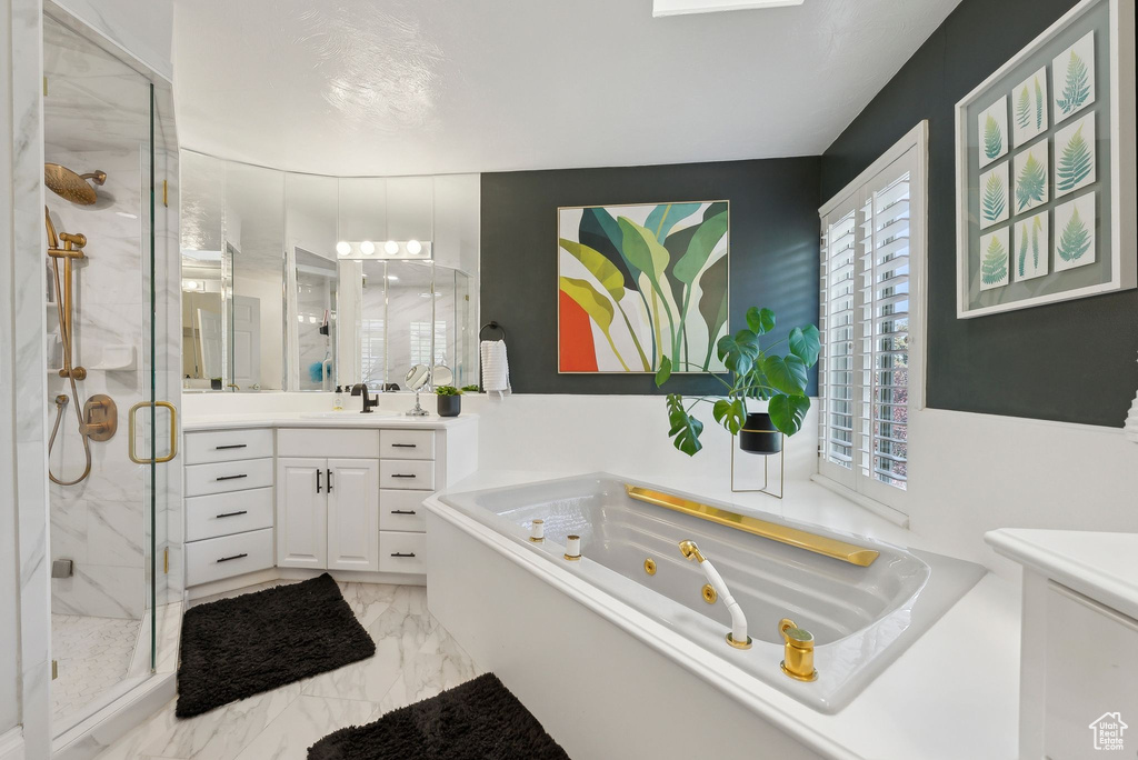 Bathroom with a stall shower, vanity, a tub with jets, and marble look tiles
