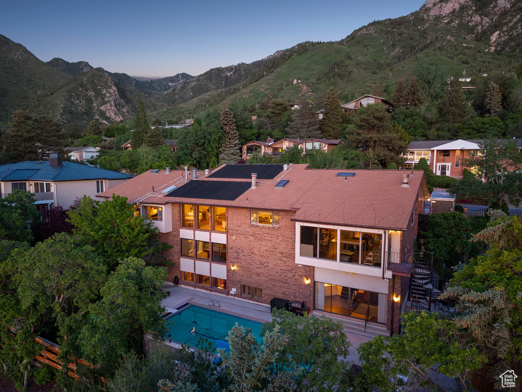 Rear view of house featuring stairway, a mountain view, an outdoor pool, and brick siding