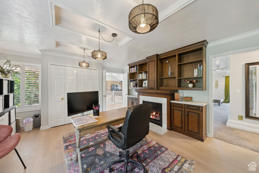 Office space with a tile fireplace, light wood-style flooring, ornamental molding, and baseboards