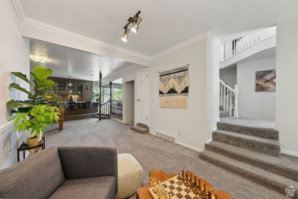 Living room with carpet floors, stairway, crown molding, and baseboards