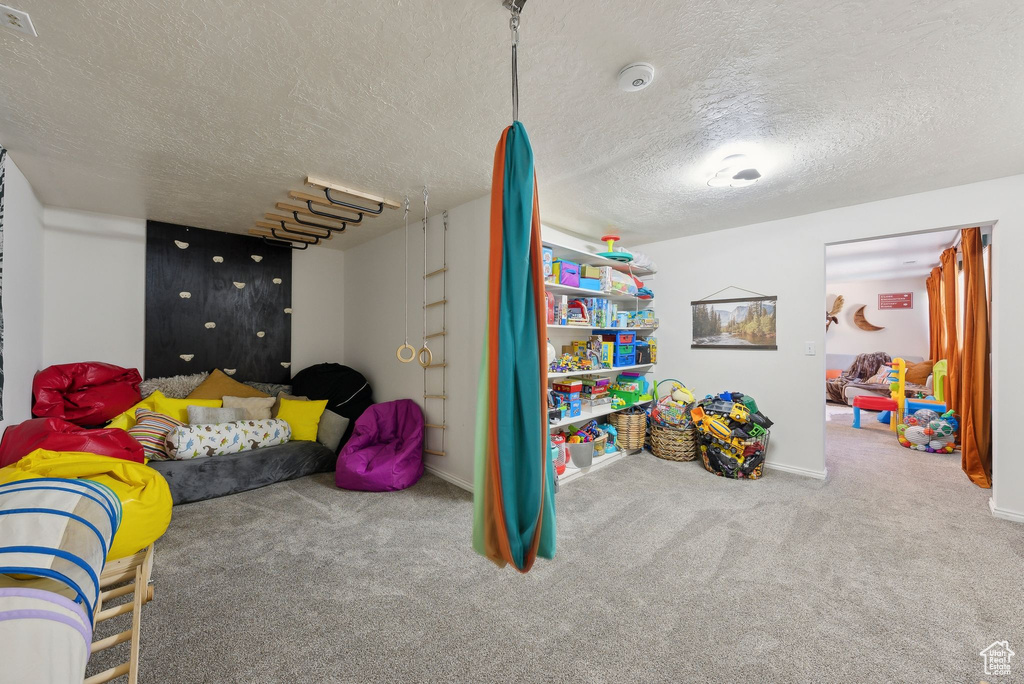 Playroom featuring carpet flooring, a textured ceiling, and baseboards