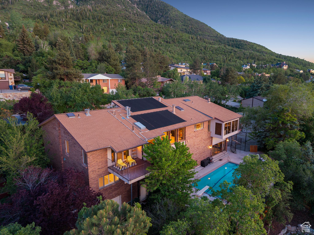 View of subject property featuring a mountainous background, a forest, and a pool area