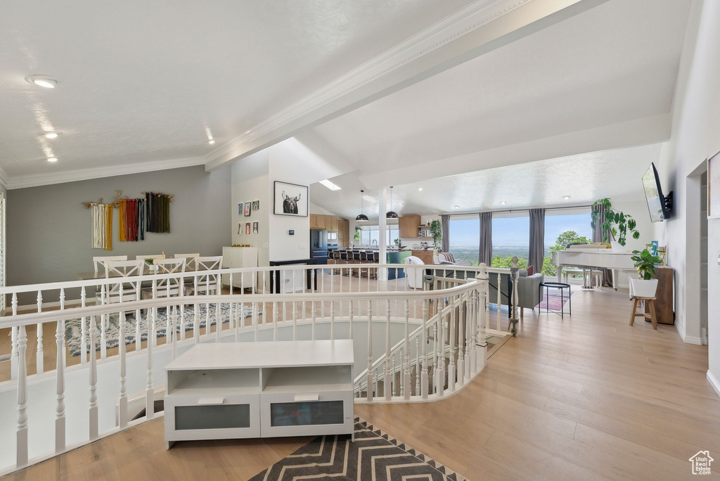 Hall with an upstairs landing, crown molding, and wood finished floors