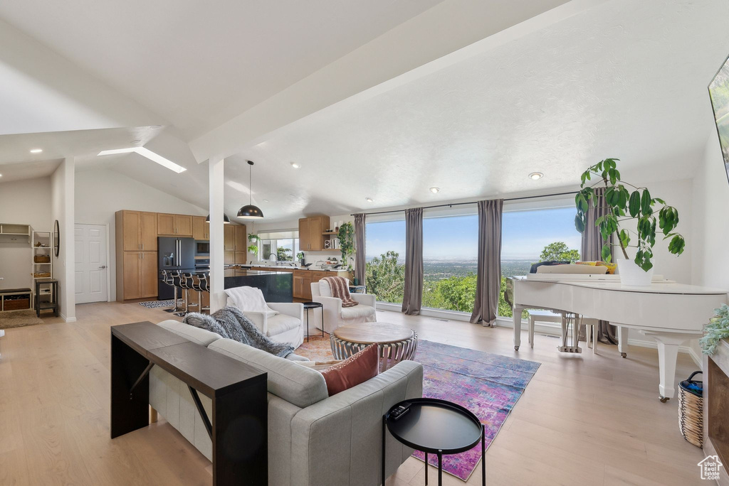 Living room featuring light wood-style flooring, vaulted ceiling, and recessed lighting