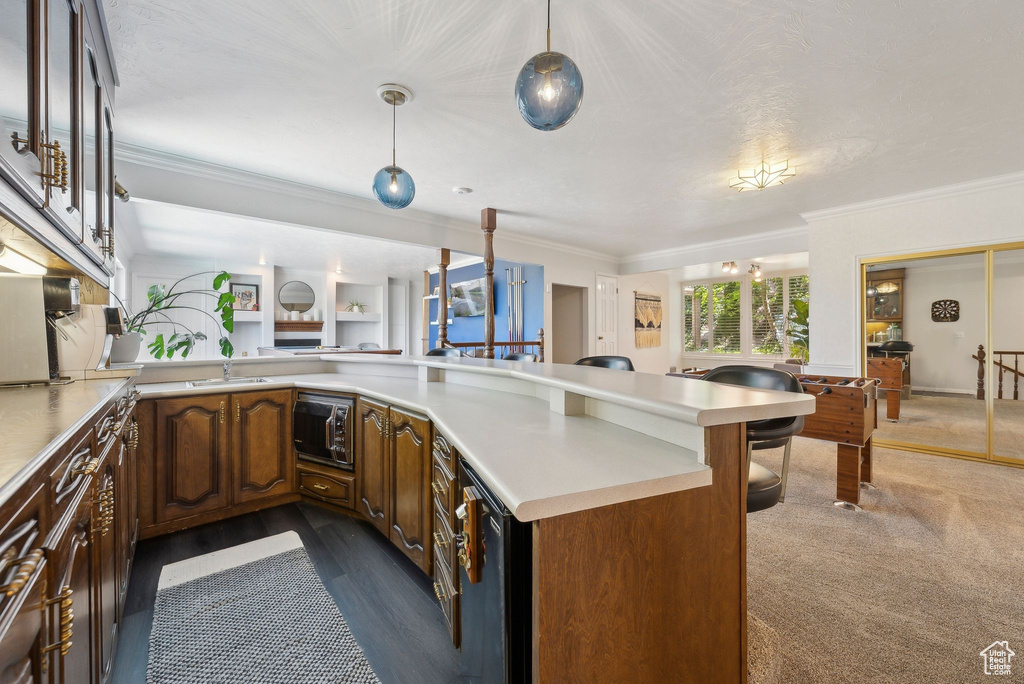 Kitchen featuring a breakfast bar, crown molding, light countertops, a sink, and a peninsula