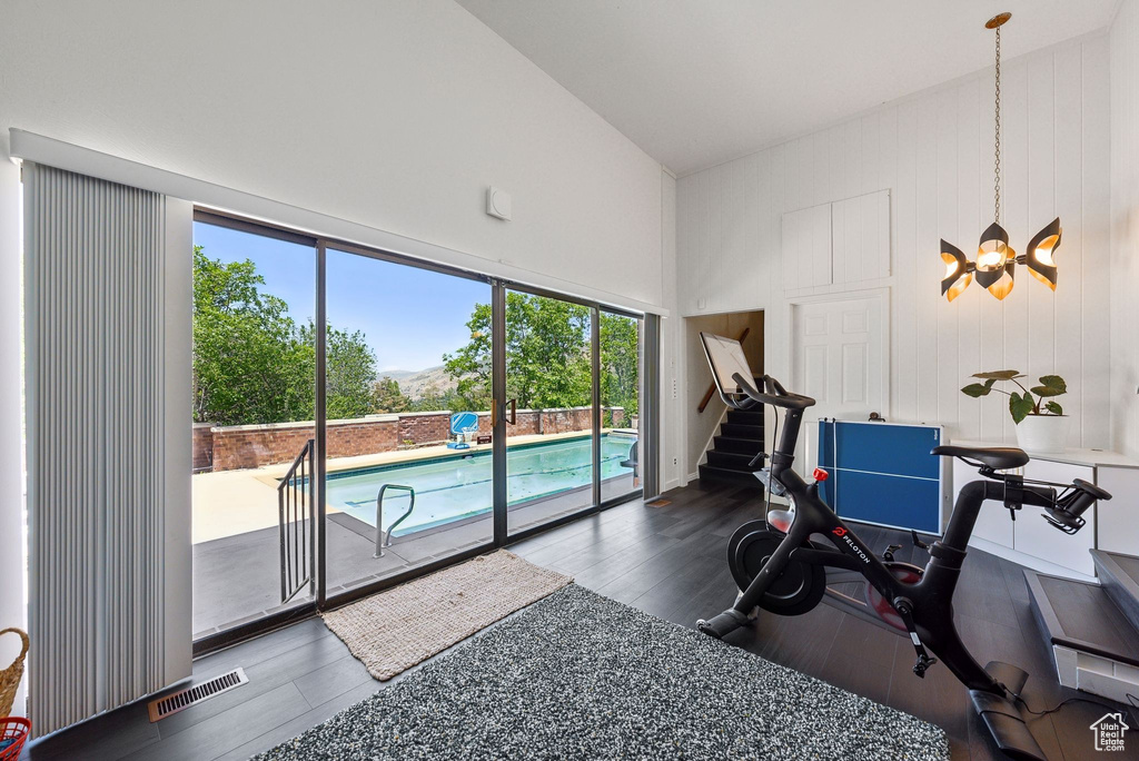 Workout area with healthy amount of natural light, a towering ceiling, wood finished floors, and a chandelier