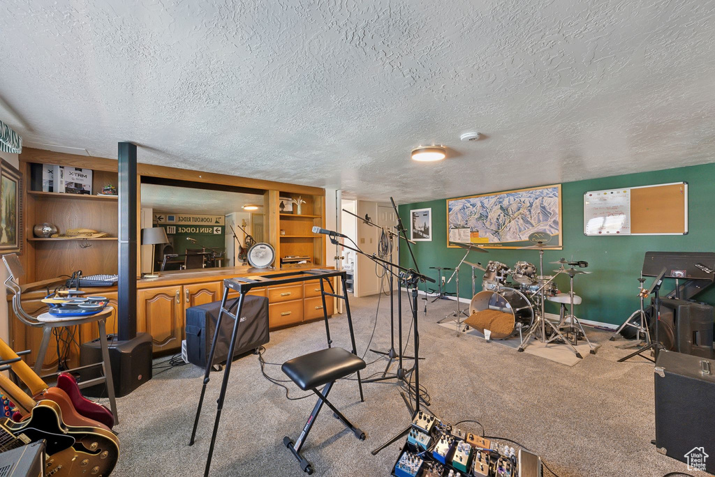 Recreation room featuring carpet, a textured ceiling, and baseboards