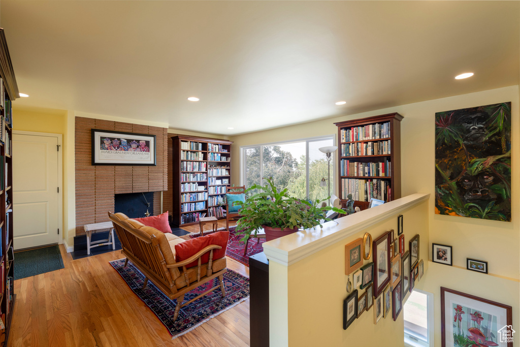 Living area with wood finished floors, a brick fireplace, and recessed lighting