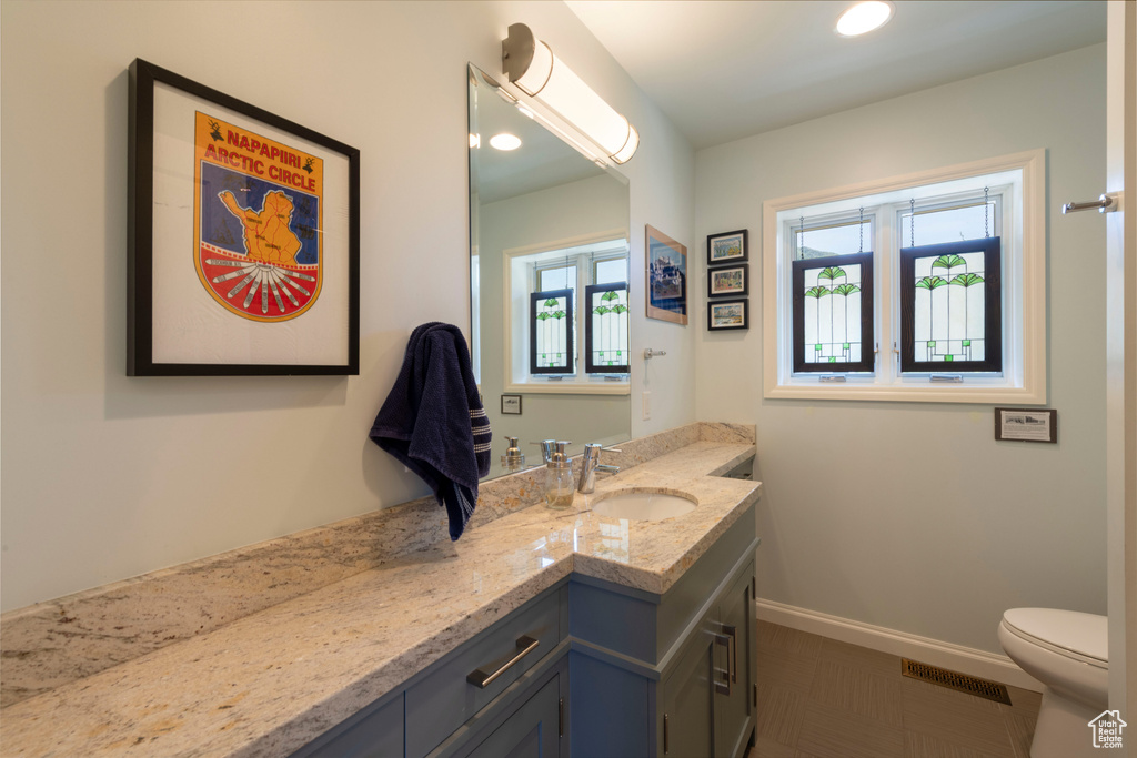 Bathroom featuring vanity, toilet, and baseboards