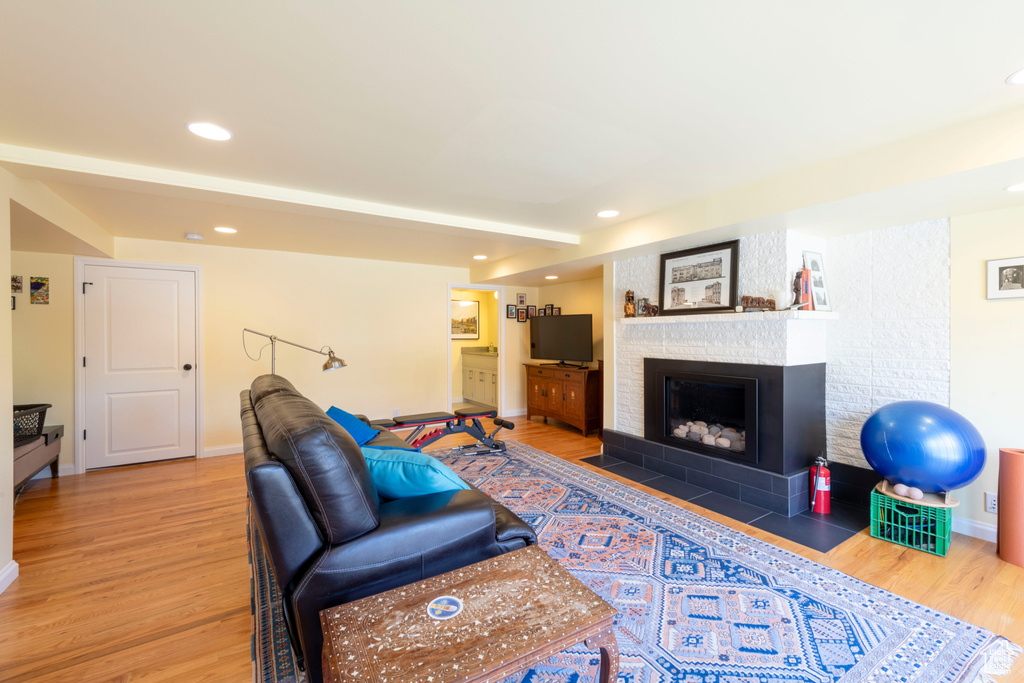 Living room with light wood-style flooring, a fireplace with flush hearth, baseboards, and recessed lighting