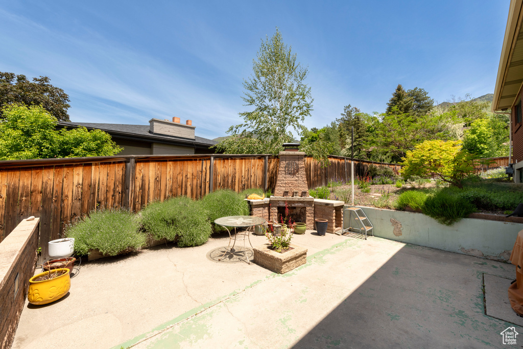 Fenced backyard featuring an outdoor stone fireplace and a patio