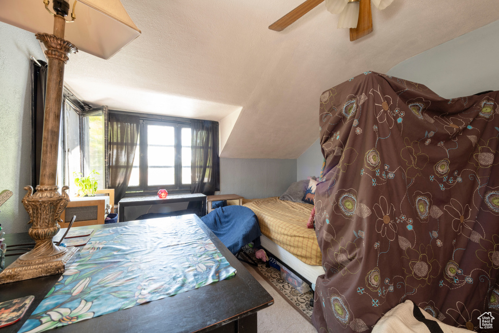 Bedroom with vaulted ceiling, ceiling fan, and carpet